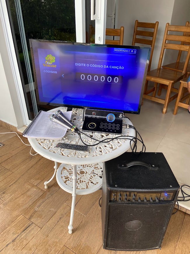 Videokê com TV, microfones e amplificador em área de festa